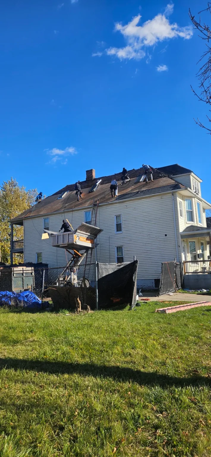Crew using a lift on a large house roof – T&M Roofing project