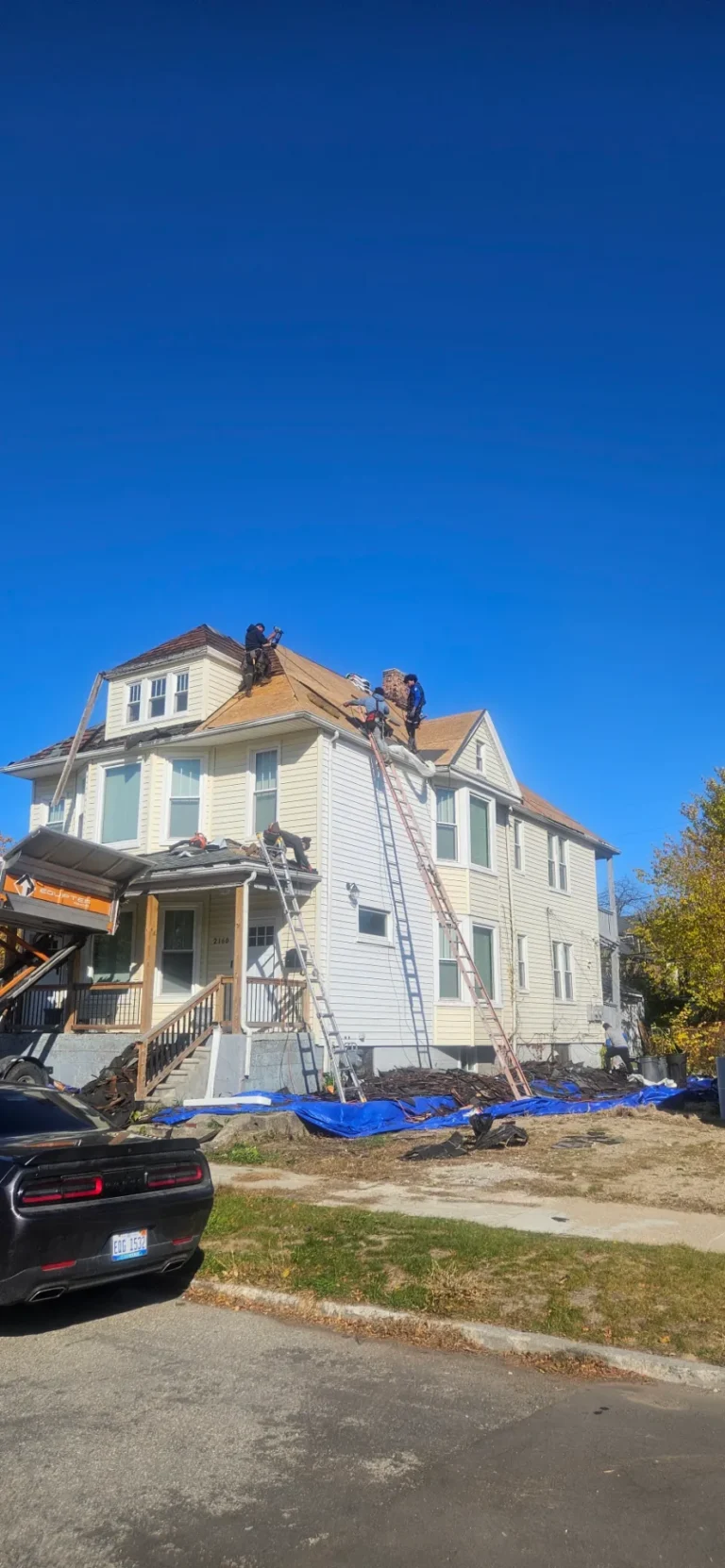 Crew tearing off a tall house roof