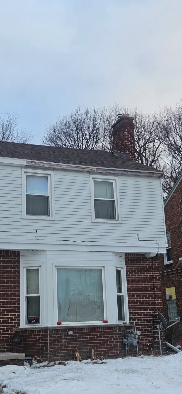 Home with white siding and a new roof installed by T&M Roofing in the fall